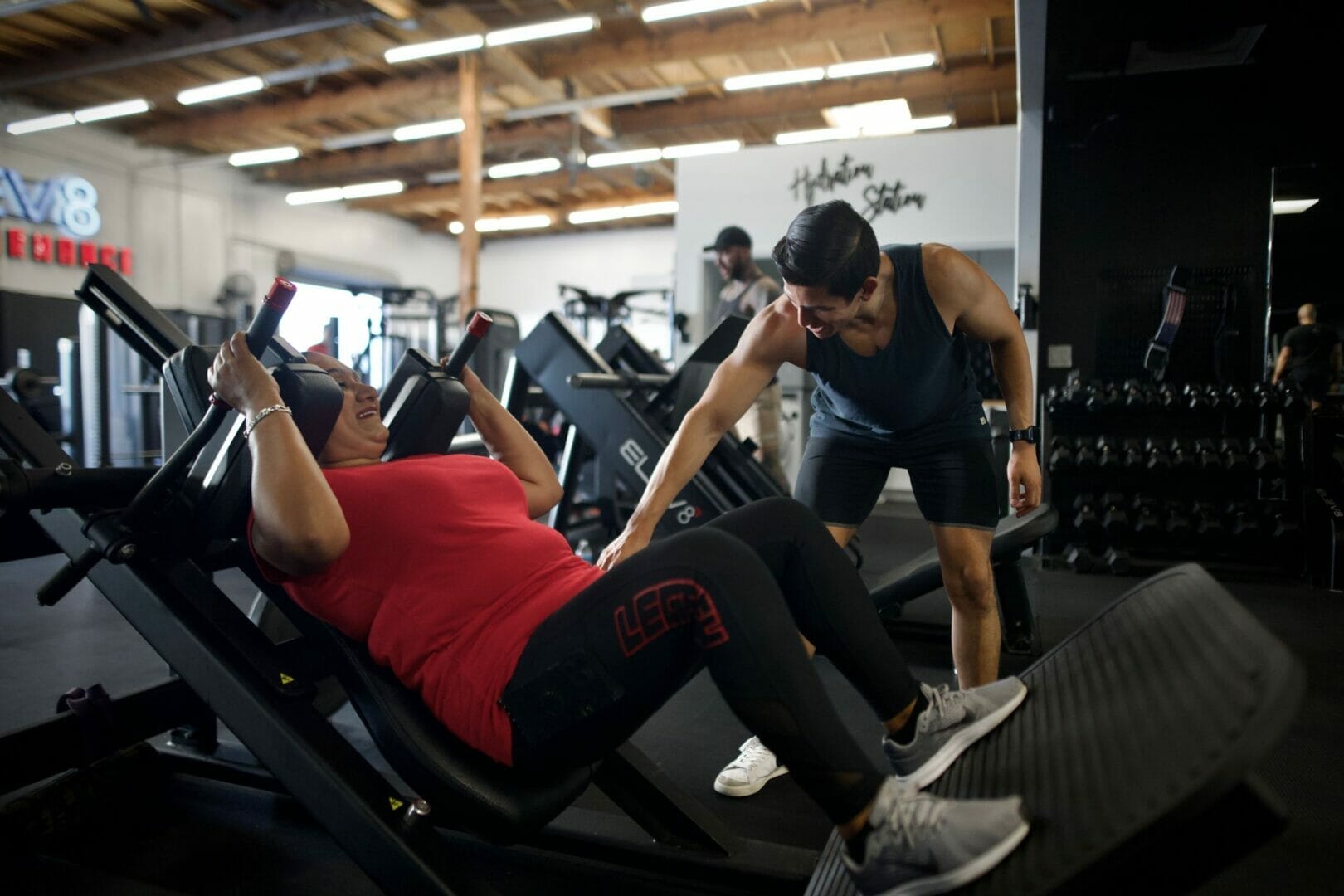Woman training legs on equipment with coach at Elev8 Performance